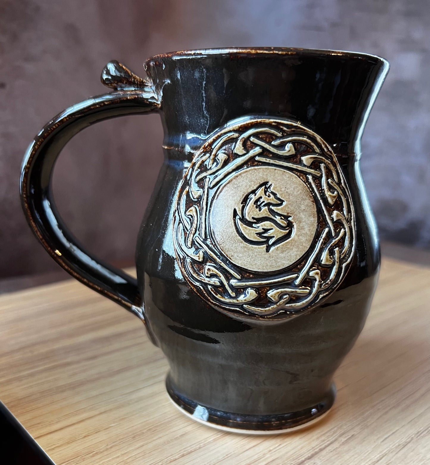 Black glazed hand thrown pottery mug with a fox and Celtic knotwork.