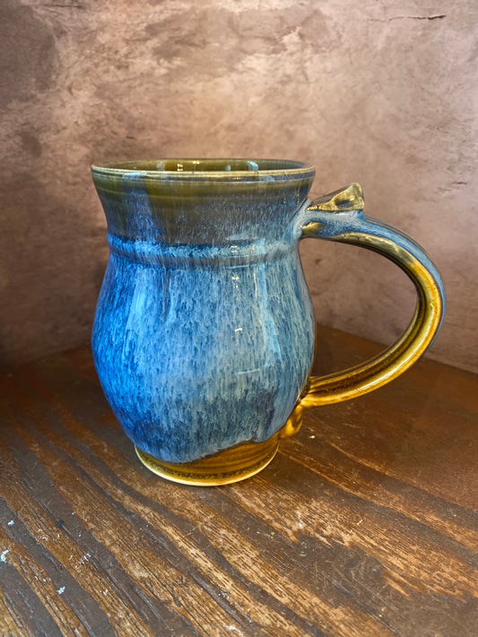back of a hand thrown pottery mug with blues and browns