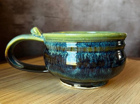 A low wide black and green soup mug with a handle