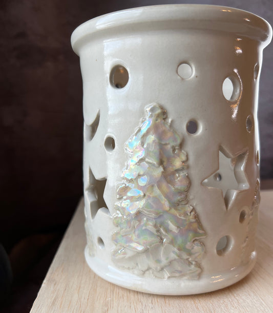 White and ivory pearl glazed candle shelter with stars, moon and circles cut out.