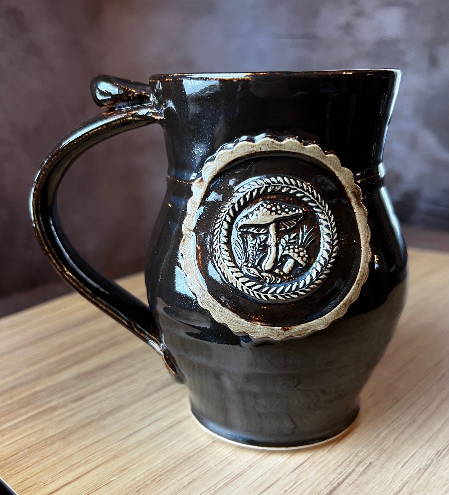Black gazed, hand thrown ceramic round belly mug with an Amanita mushroom medallion