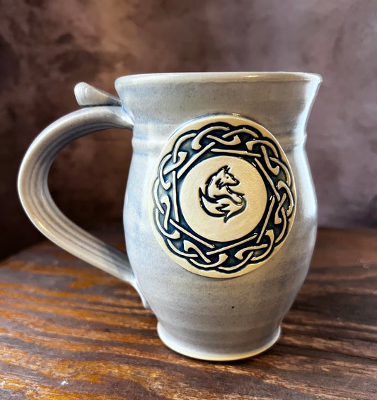 Hand thrown ceramic mug with a celtic knot circle containing a fox in the center.
