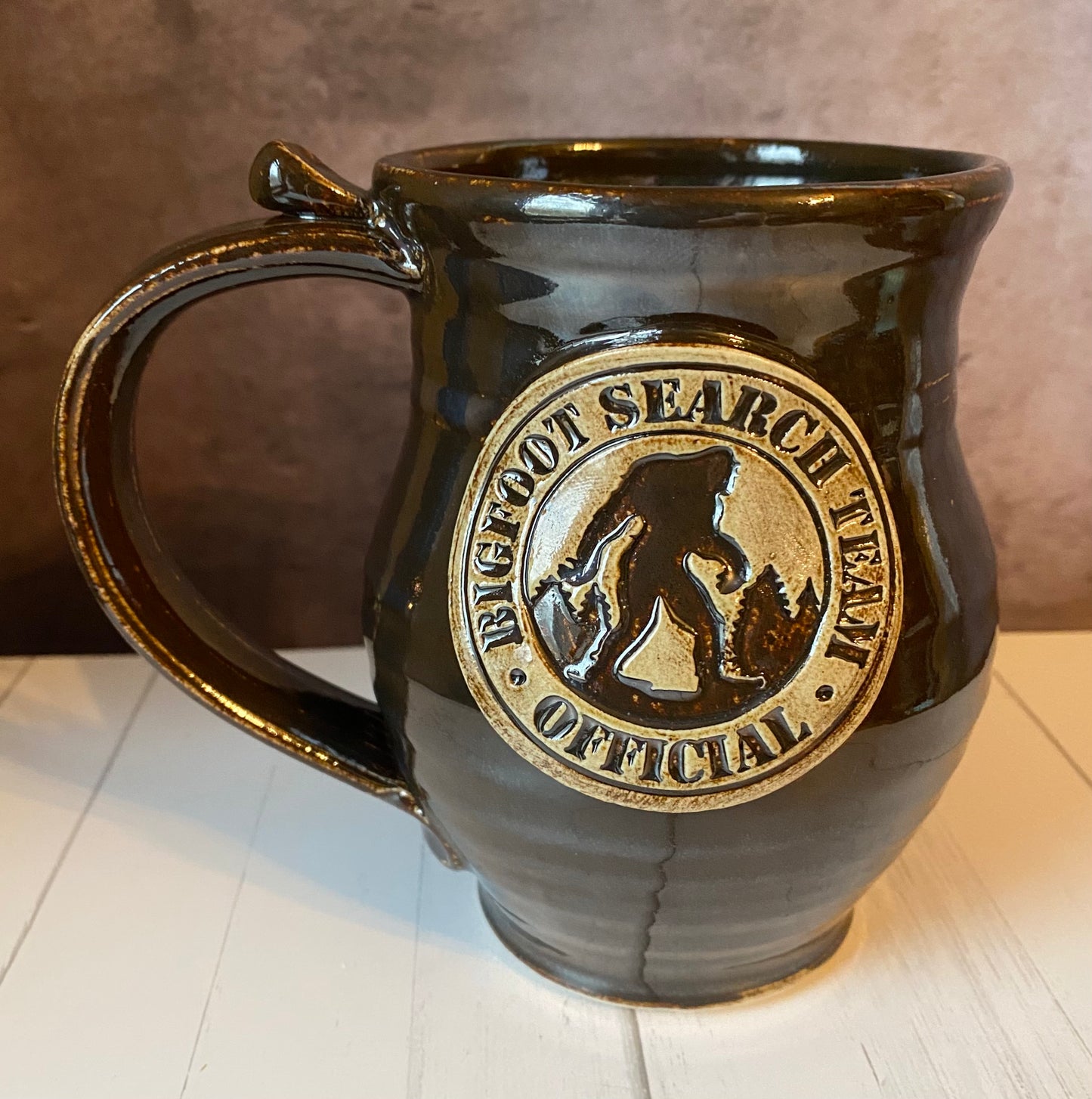 hand thrown round belly mug with Bigfoot search team medallion 