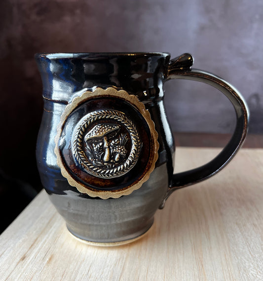 Left handed Black glazed mug with Amanita mushrooms in a medallion.