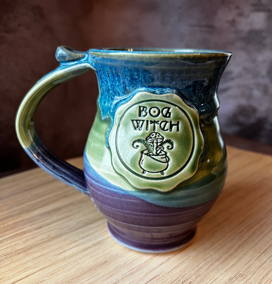 Hand thrown ceramic mug with a Bog Witch medallion.