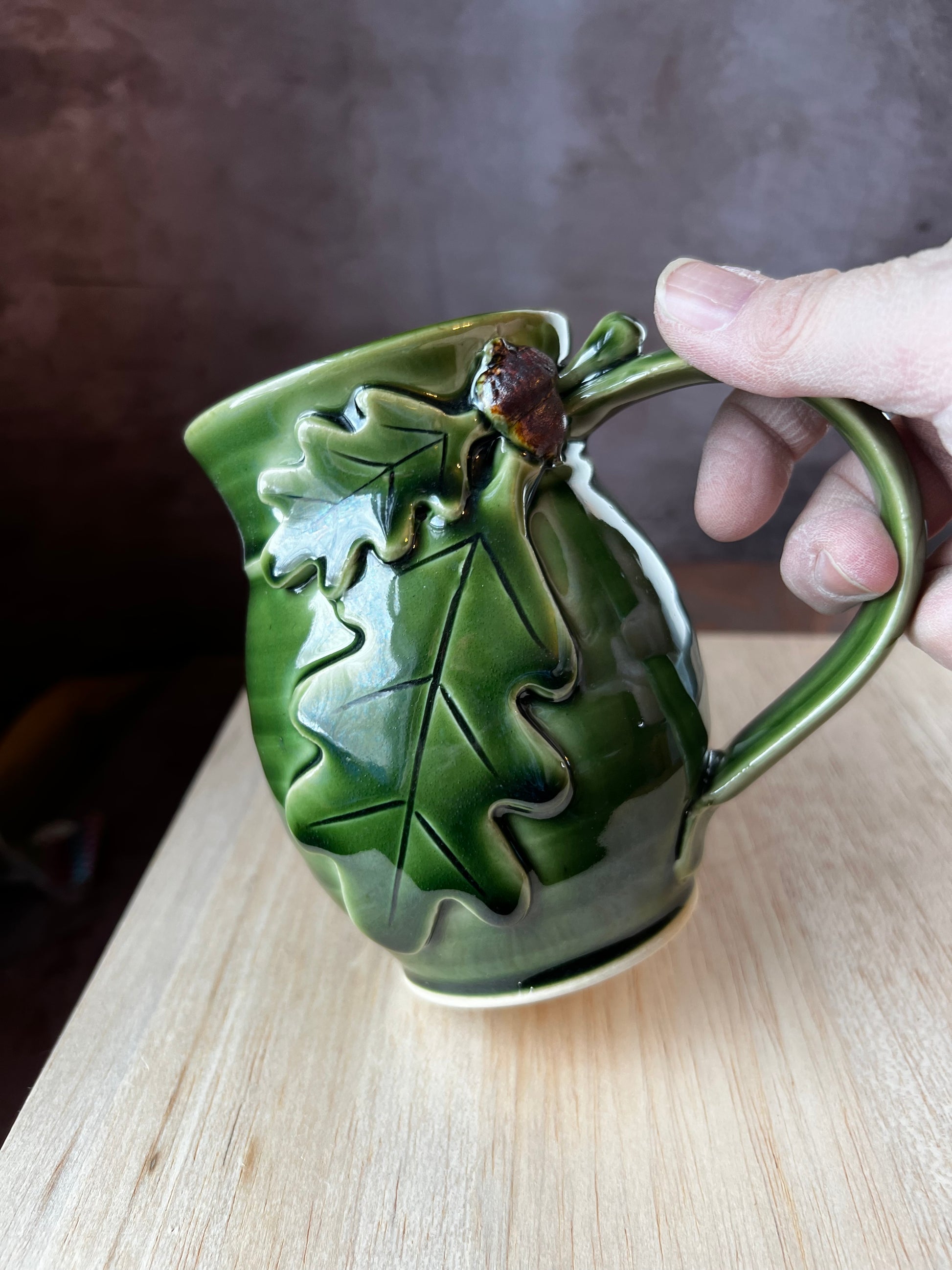Left-handed ceramic oak leaf mug in green with contrasting brown acorn