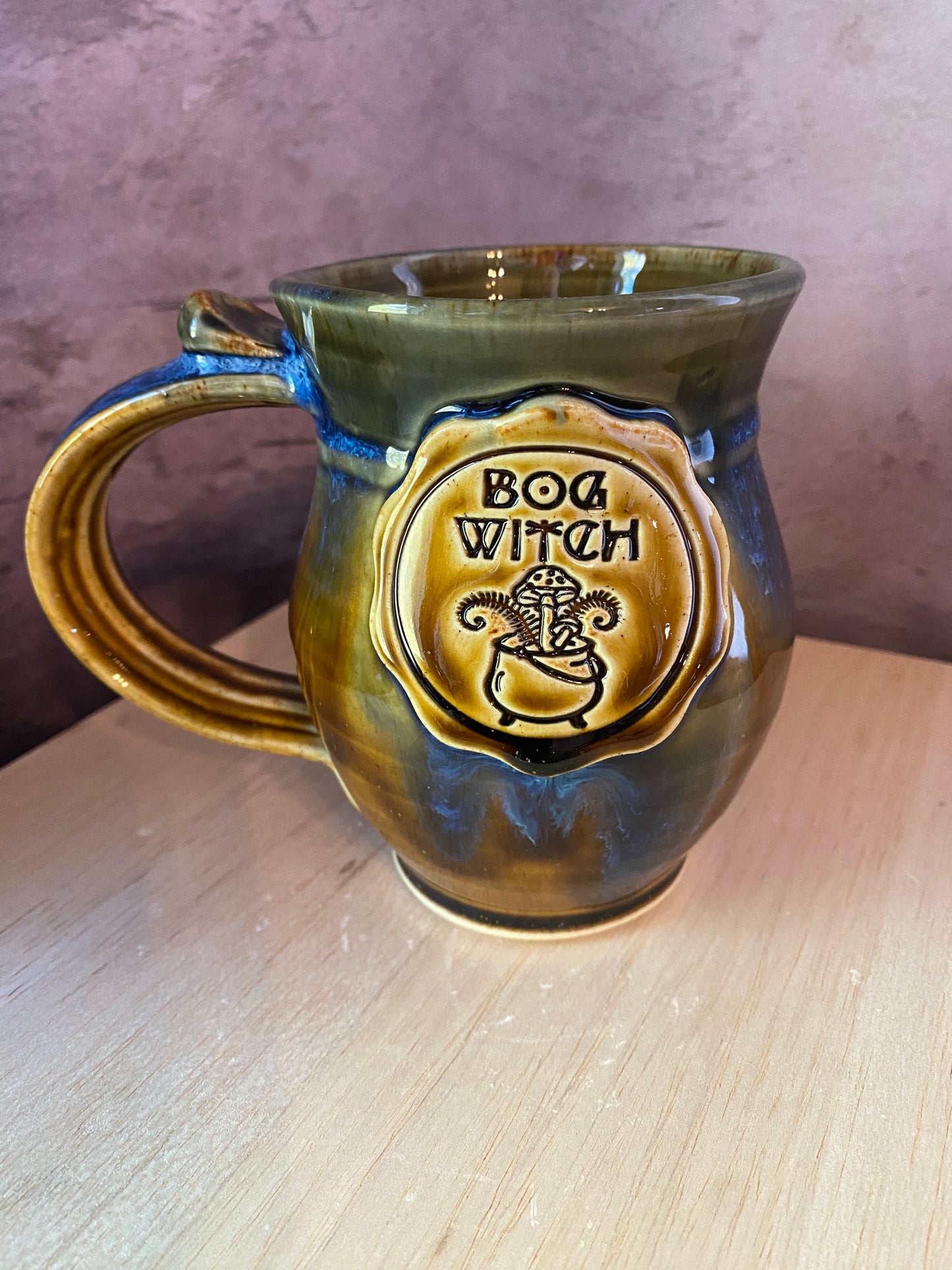 Bog Witch medallion mug hand thrown with swirls of blue glaze on a brown.