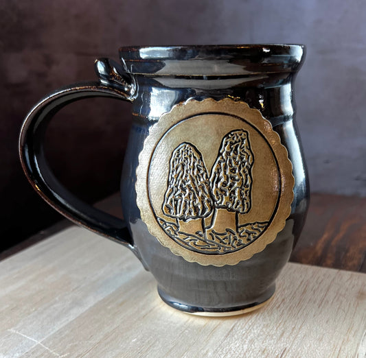 Black mug with a gold emblem featuring Morel mushroom medallion.