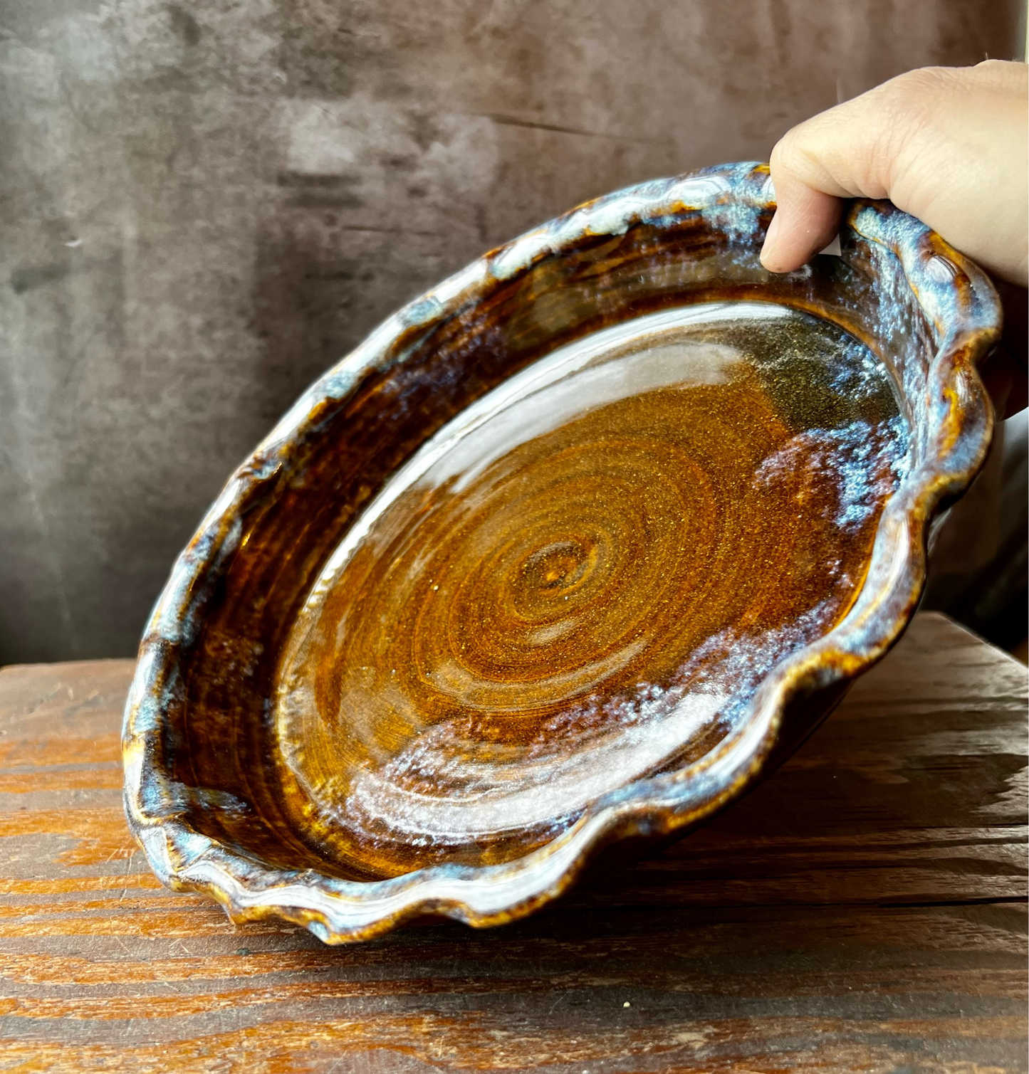 A beautiful deep golden brown glazed stoneware  pie pan with a ruffled edge.