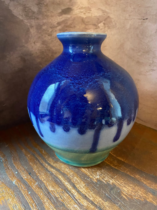 Rounded stoneware vase with cobalt blue glaze dripping over lighter blue and green glaze. 
